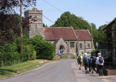 Photo of walkers with St John the Evangelist Church, Hinton Martell, in the background– May 31, 2025