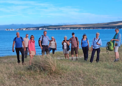 Group photo with Handfast Point in the distance – July 17, 2025