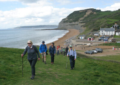 Photo of walkers climbing Doghouse Hill from Seatown with Golden Cap is in the background – April 18, 2026