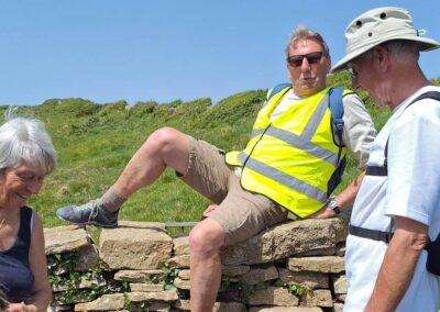 Photo 2 of walkers negotiating a tricky stone stile – May 23, 2026