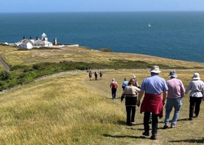 Photo of walkers with Anvil Point Lighthouse in the background – June 13, 2026