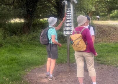 Photo of walkers playing one of the percussion instruments set up around the lake in the park – July 1, 2026